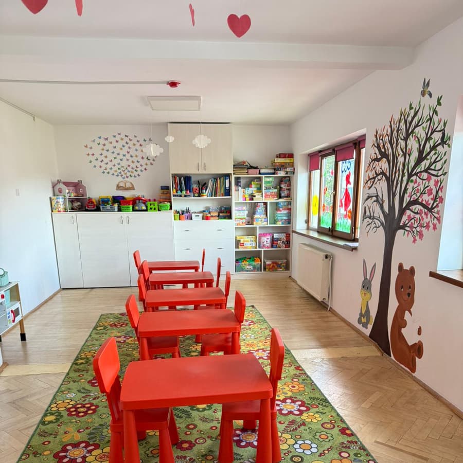 Sala cu covor înflorat, un copac pictat pe perete cu ursuleț și iepuraș