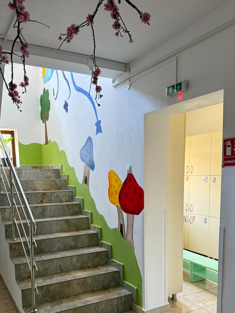 Scara pictată cu un deal verde și ciuperci, spre vestiar